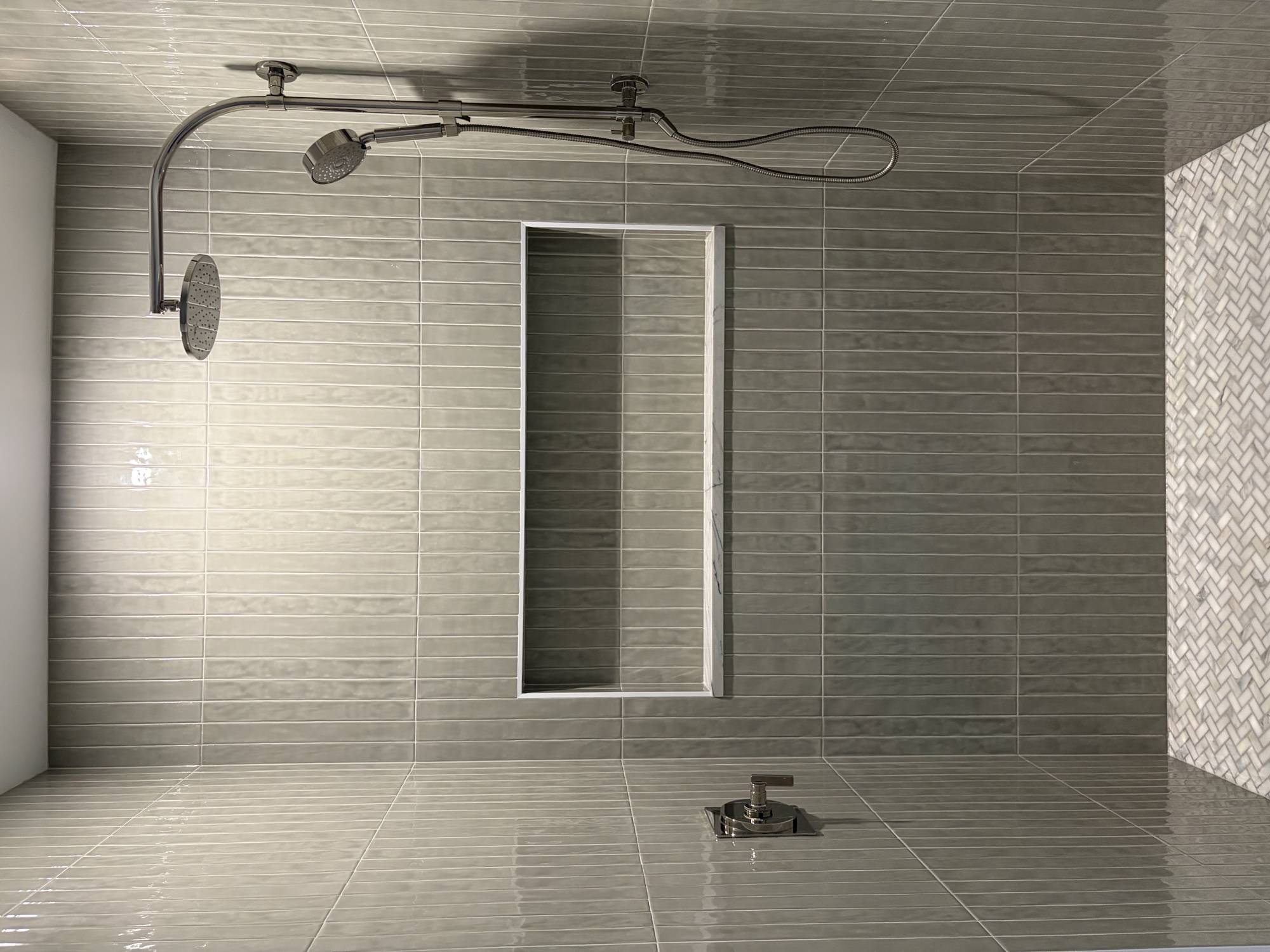 Finished custom shower with horizontal porcelain tile, vertical glass-mosaic accent stripe, recessed niche, chrome fixtures — after tile installation by Konar Bros Tile Co. Tampa Bay